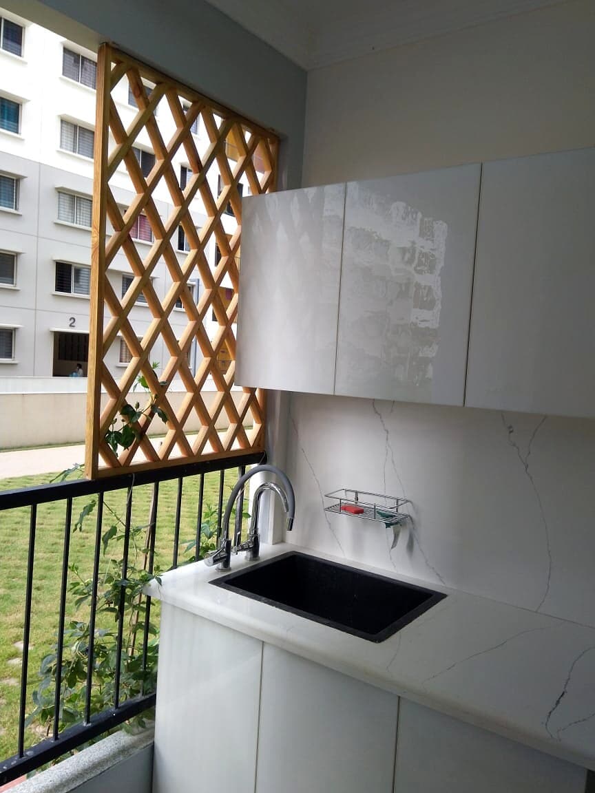 Balcony utility sink with white cabinets and wood lattice privacy screen