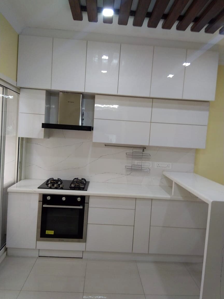 White modular kitchen with overhead cabinets and built-in hob